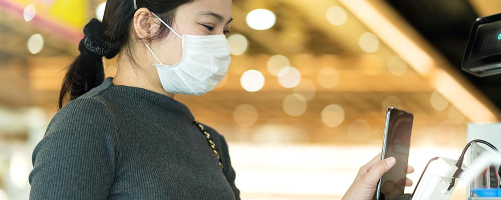 Woman wearing mask using touchless kiosk